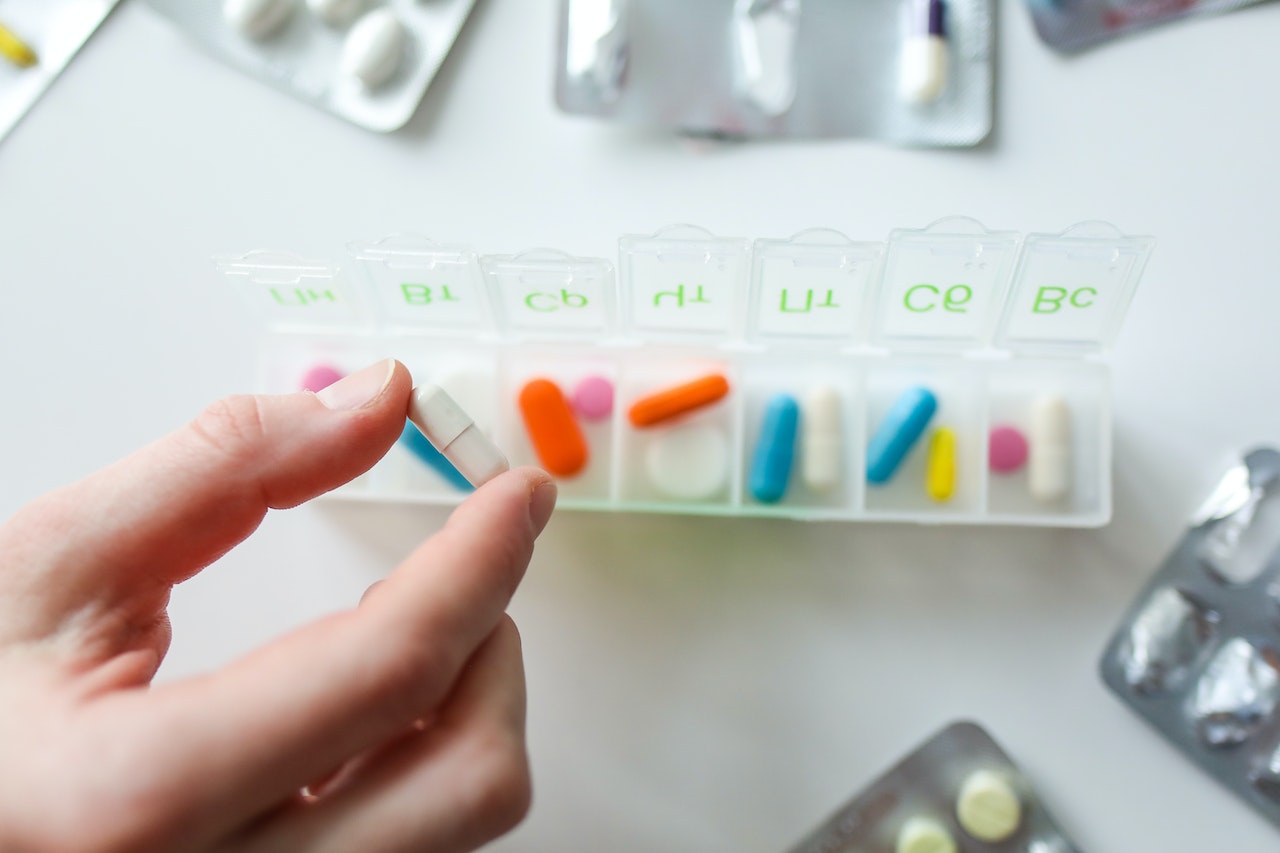 cancer treatment coverage Singapore: A hand holding a pill in a pill box

Description automatically generated with low confidence