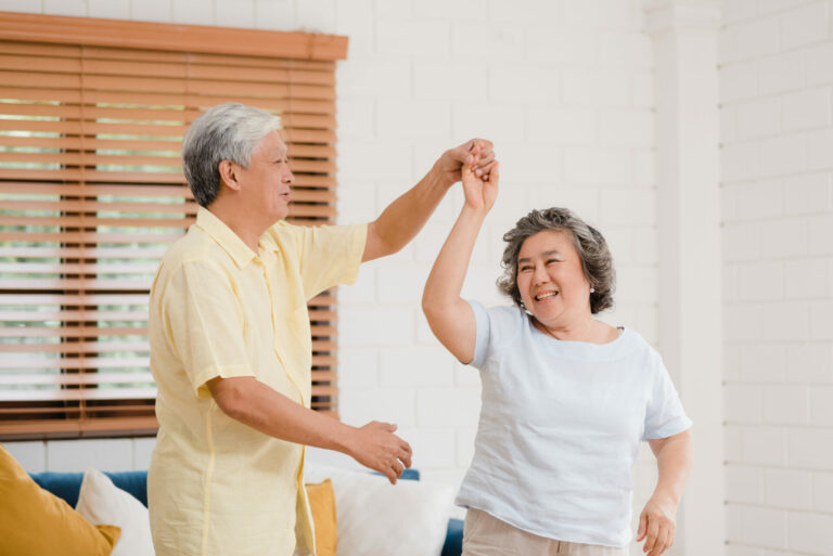 Asian elderly couple dancing together while listen to music in l