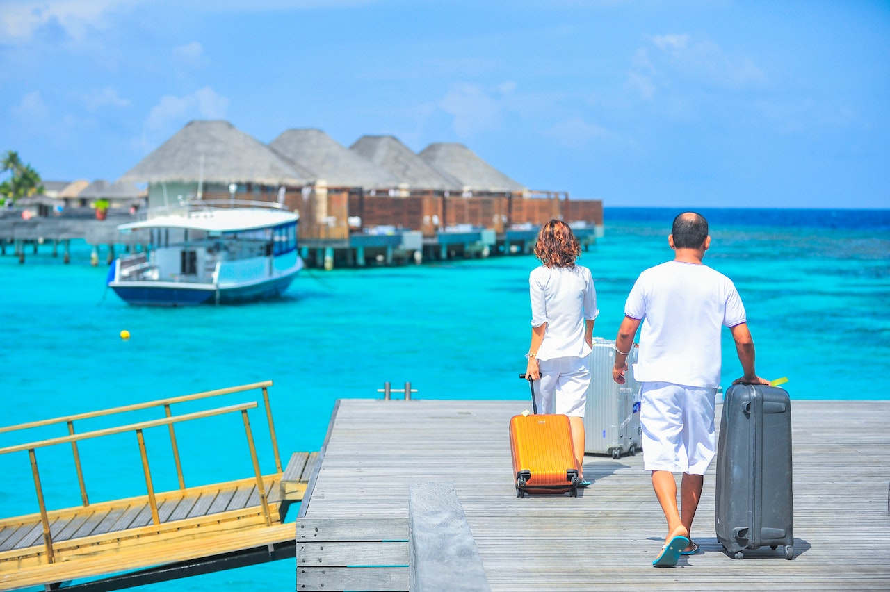 A person and person walking on a dock with luggage

Description automatically generated