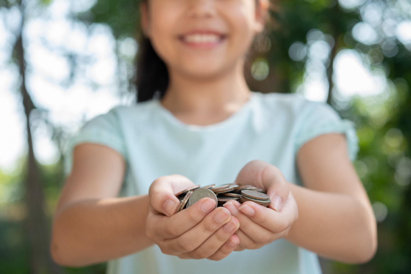 A child holding coins in her hands Description automatically generated