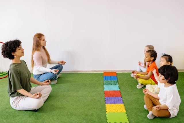 A group of people sitting on the floor with their hands in the air Description automatically generated