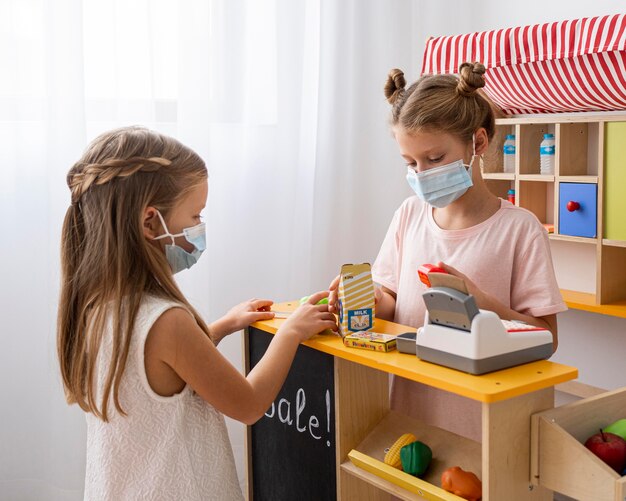 Kids playing together indoors while wearing medical masks