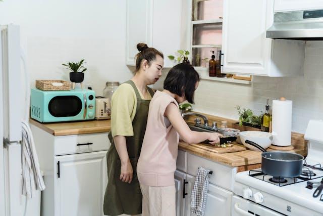 Two women standing in a kitchen Description automatically generated